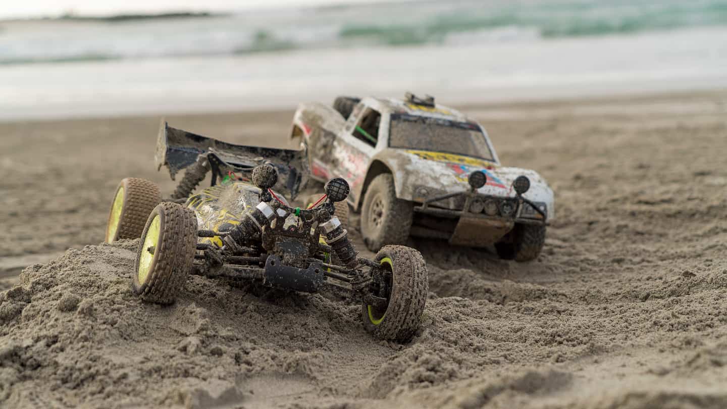two rc cars parked on a sandy beach